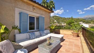 Une terrasse avec un canapé, des meubles en osier et des plantes en pot.