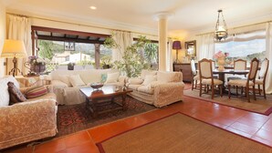 A spacious living room with a sofa, coffee table, and dining area, featuring a view through a large window. - Villa 'Font' with Mountain View, Wi-Fi and Air Conditioning (Mancor de la Vall)