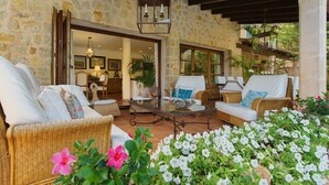 A stone-walled outdoor seating area with wicker furniture, a glass table, and potted plants. - Villa 'Font' with Mountain View, Wi-Fi and Air Conditioning (Mancor de la Vall)