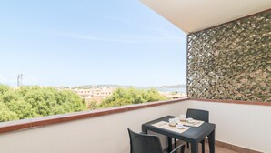 A balcony with a table and chairs, a decorative wall, and a view of buildings and greenery. - Apartment 'La Gioia' with Sea View, Wi-Fi and Air Conditioning (Palau)