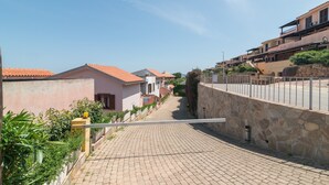 A residential street with houses, a paved road, and a stone wall. - Apartment 'La Gioia' with Sea View, Wi-Fi and Air Conditioning (Palau)