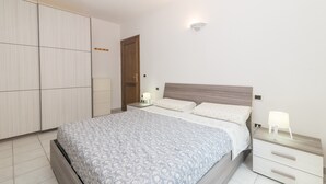A bedroom with a bed, nightstands, a wardrobe, and a ceiling light. - Apartment 'La Gioia' with Sea View, Wi-Fi and Air Conditioning (Palau)