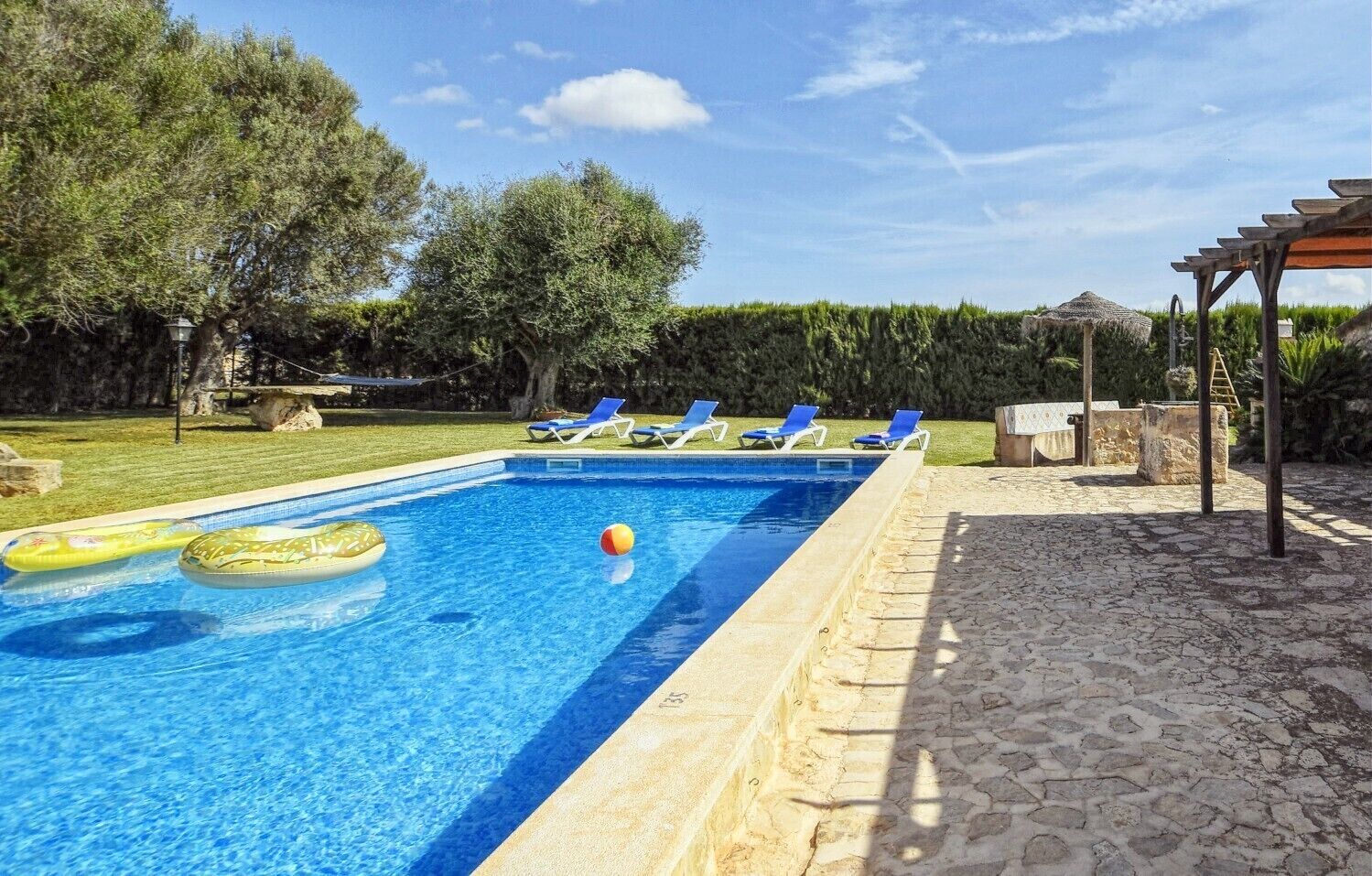 Una piscina rectangular con agua azul cristalina, rodeada por una terraza de piedra.
