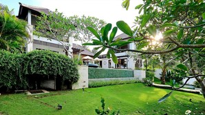 A well-maintained garden with a lawn, a stone wall, and a variety of plants. - Lumi Villa Uluwatu (Pecatu)