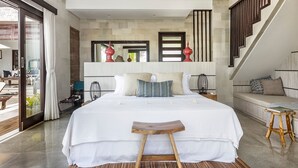 A modern bedroom with a large bed, a wooden stool, and a bench. - Lumi Villa Uluwatu (Pecatu)