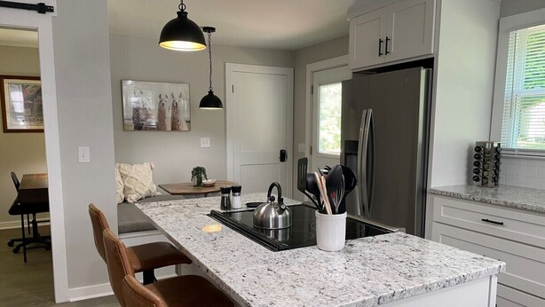 Una cocina moderna con una isla central, electrodomésticos de acero inoxidable e iluminación colgante.