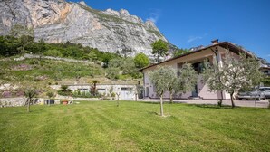 Ein Haus mit Blick auf einen Berg, einem grünen Rasen und einem in der Nähe geparkten Auto.