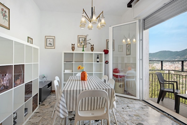 A dining area with a table, chairs, and a view of the city through a glass door.