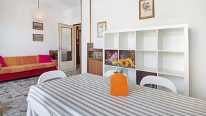Ein Essbereich mit einem gestreiften Tisch, einer orangefarbenen Vase und einem weißen Stuhl.
