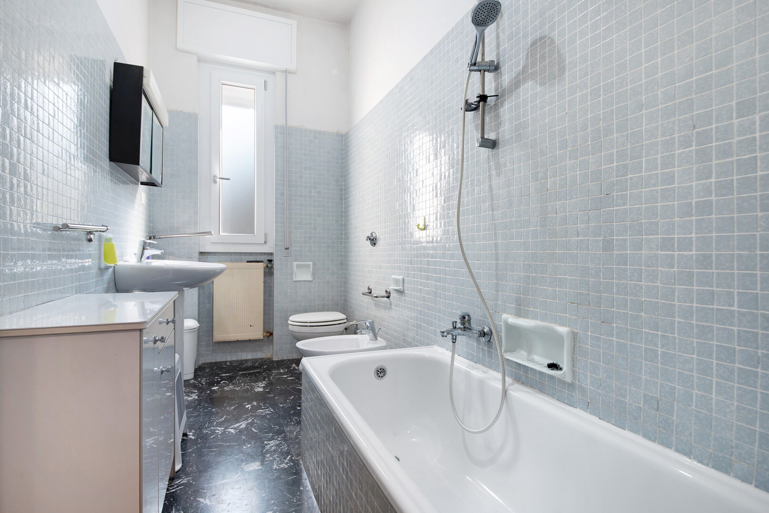Een badkamer met een bad, toilet, wastafel en douche.
