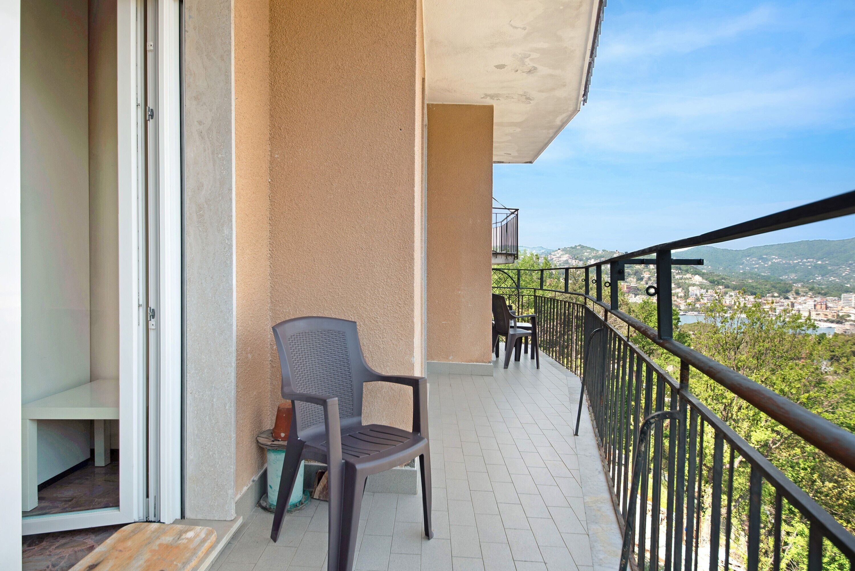 Un balcone con una sedia, un tavolino e vista sulla città e sulle colline.