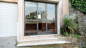 Ein Gebäude mit großem Fenster, Garagentor und einer Steinmauer mit Grünpflanzen.