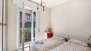 Ein Schlafzimmer mit einem Bett, einem Nachttisch, einer Lampe und einer Balkontür.