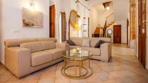 A living room with two beige sofas, a glass coffee table, and a staircase leading to an upper level. - Holiday Home 'Ca La Senyora Dels Arbres' with Private Pool, Terrace and Wi-Fi (Arta)