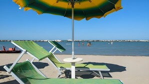 A beach with lounge chairs and an umbrella, a rocky breakwater in the background, and calm water. - Holiday Apartment "Luna" with Sea View, Shared Garden & Wi-Fi (Rimini)