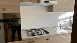 A modern kitchen with a gas stove, stainless steel sink, and wooden cabinetry. - Holiday Apartment "Luna" with Sea View, Shared Garden & Wi-Fi (Rimini)