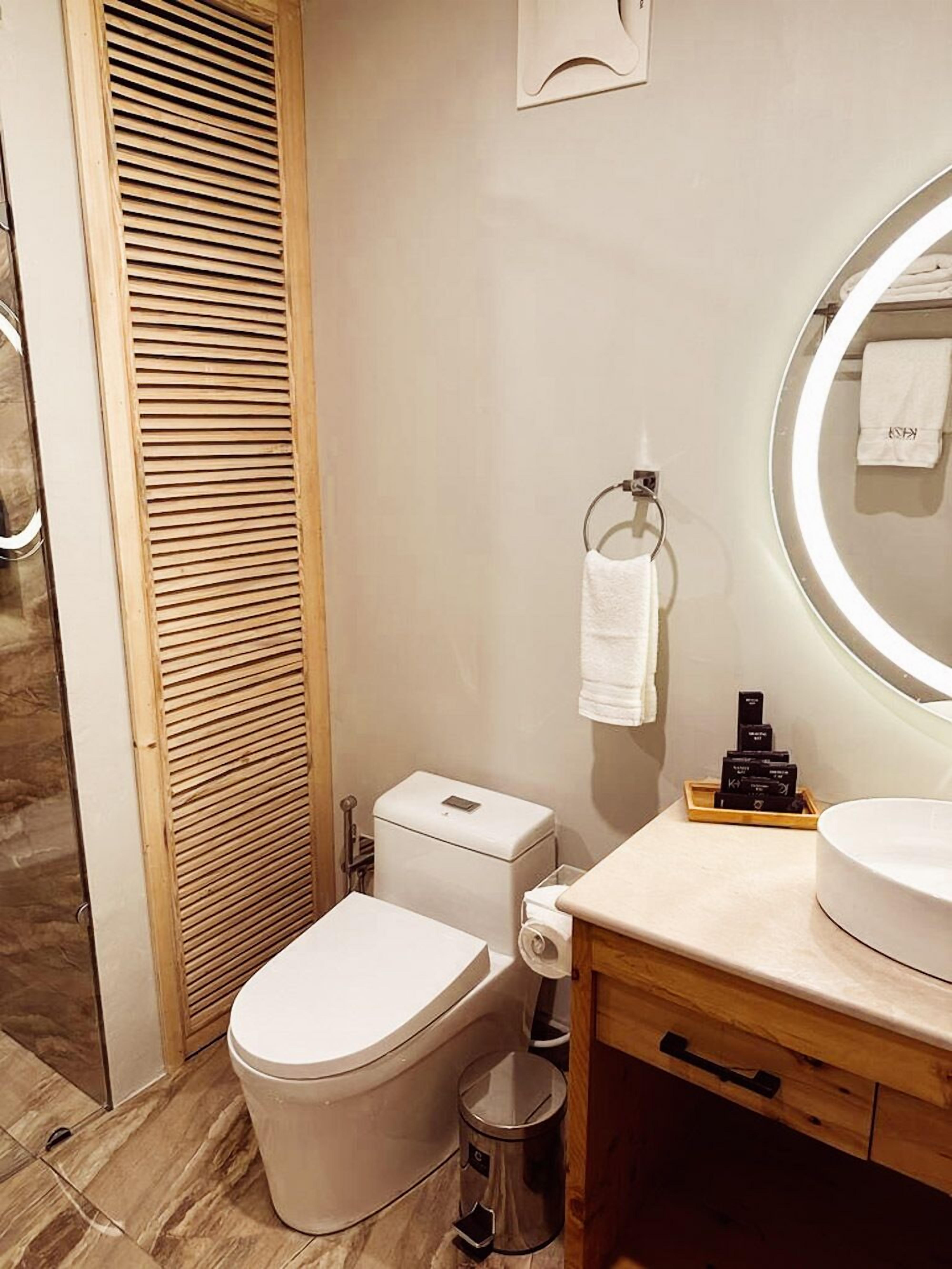 A modern bathroom with a toilet, bidet, sink, and mirror.