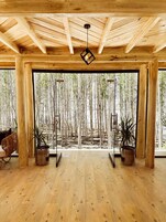 A room with a wooden ceiling, large windows, and two potted plants.