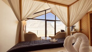 Un dormitorio con un ventanal grande, una cama, una silla y una mesa.