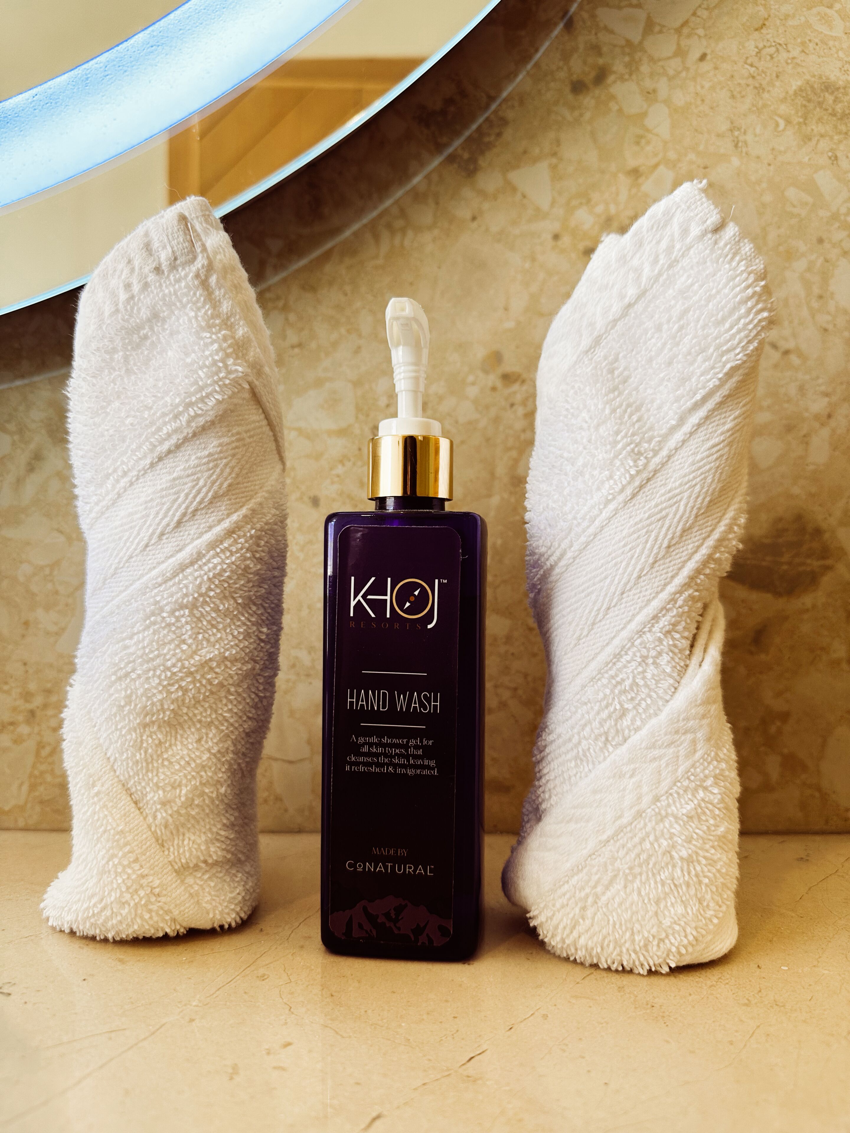 A hand wash product with a pump dispenser, placed between two towels on a bathroom counter.