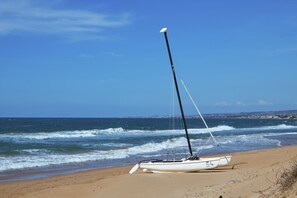 A sailboat on a sandy beach with the ocean in the background. - Dune (Scicli)