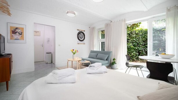 Ein modernes Hotelzimmer mit einem großen Bett, einem Schreibtisch, einem Stuhl und Blick auf Grünflächen.