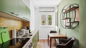 A compact kitchen with a dining area, featuring a window, a green cabinet, and a wooden table. - Arbio I Cozy apartment near Ku`damm (Berlin)