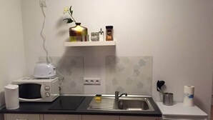 Een kleine keuken met een magnetron, spoelbak en kleine koelkast.