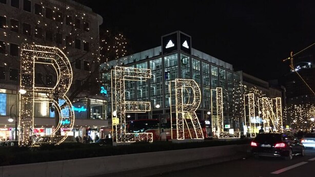 Een grote, verlichte bord met daarop in neonletters de tekst 'BERLIN' langs een straat bij nacht.