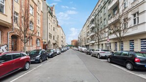 A street lined with parked cars and multi-story buildings.
