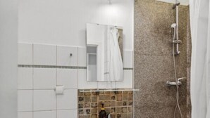 A bathroom with a white sink, a mirror, a shower, and a toilet.