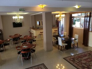 A hotel lobby with multiple seating areas, a bar, and a television screen.