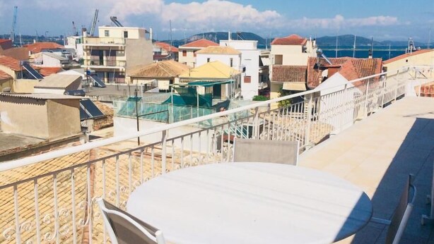 A rooftop terrace with a round table and chairs, overlooking a residential area with buildings and a clear sky. - HOTEL MINOS (Preveza)