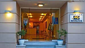 A hotel entrance with a glass door, a sign reading "HOTEL MINZE", and two potted plants on the steps. - HOTEL MINOS (Preveza)