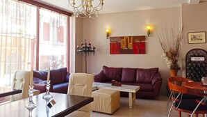 A living room with a sofa, chairs, a coffee table, and a dining table with candles. - HOTEL MINOS (Preveza)