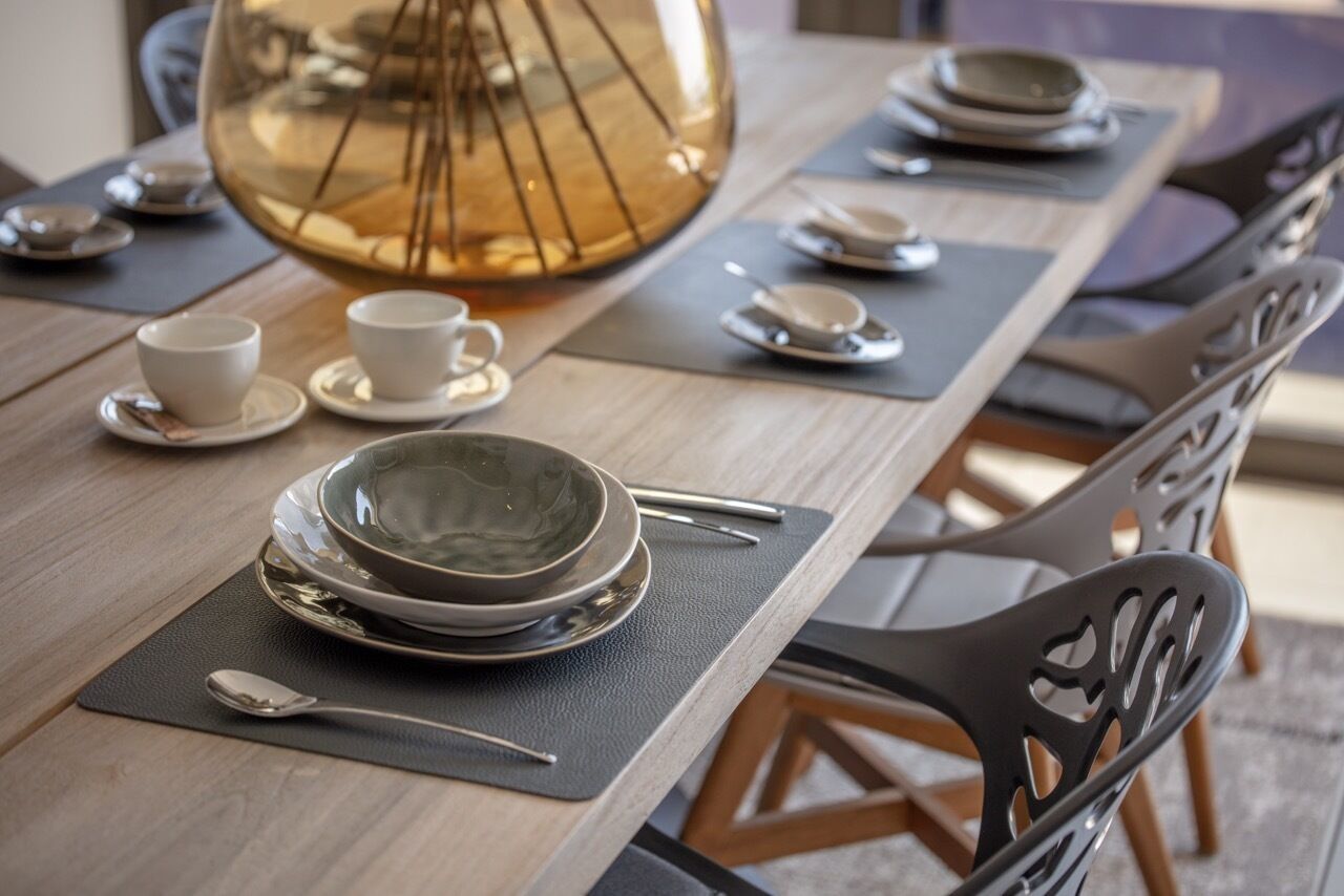 Een eettafel gedekt met borden, kommen, bekers en bestek, met een decoratief glazen middelpunt.