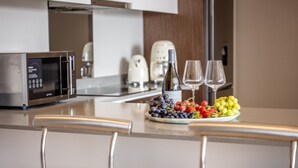 A modern kitchen with a stainless steel microwave, a coffee maker, and a plate of grapes and strawberries. - Azalia Apartments (Sandton)