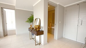 A spacious hallway with a vanity table, a mirror, and a potted plant. - Azalia Apartments (Sandton)