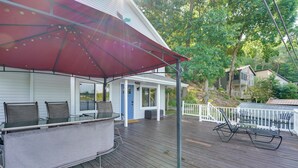 A covered outdoor seating area with a table and chairs, a red umbrella, and a white fence. - Big Pine Island Lake Cottage w/ Boat Dock & Kayaks (Belding)