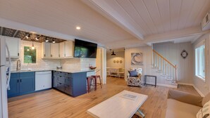 A spacious kitchen with a large island, wooden flooring, and a dining area with a staircase. - Big Pine Island Lake Cottage w/ Boat Dock & Kayaks (Belding)