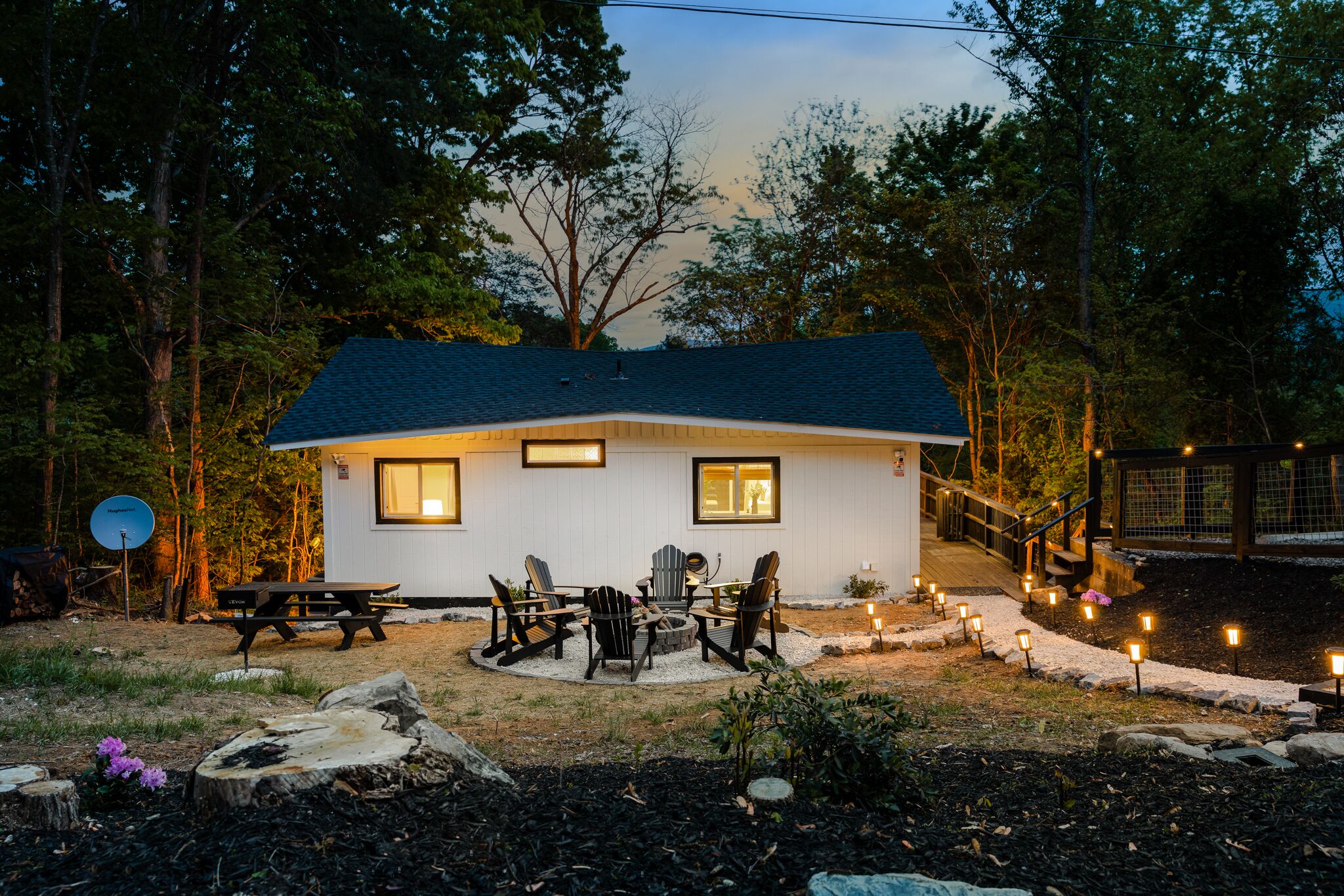 A small house with a dark roof, a picnic table, and outdoor seating.