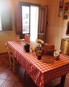 A dining area with a checkered tablecloth, chairs, and various food items. - Tobia's House  (Giuggianello)