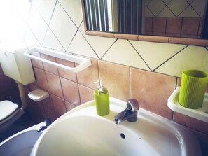 A bathroom with a sink, a mirror, a toilet, and a soap dispenser. - Tobia's House  (Giuggianello)