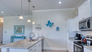 A modern kitchen with granite countertops, stainless steel appliances, and decorative wall art. - Get ready to enjoy Sunny Daze on the coast (Rockport)