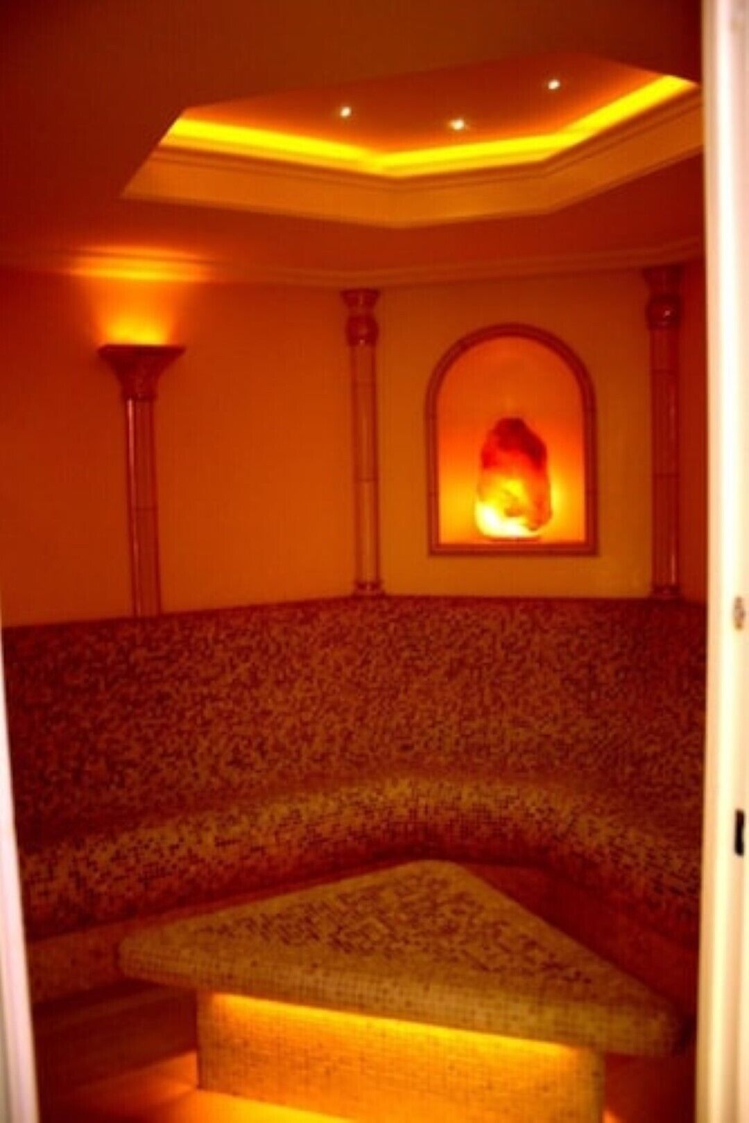 Una habitación con poca luz, pared con diseño, un pequeño rincón de estar y un adorno en la pared.