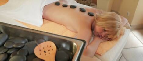 A person receiving a hot stone massage with stones placed on their back.