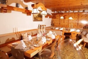Un comedor con mesas y sillas de madera, una araña y un techo de madera.