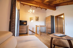 A hotel room with a bed, a TV, a wooden table, and a door.
