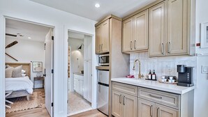 A modern kitchen with beige cabinets, a microwave, a coffee maker, and a refrigerator. - Inn History Grand Canyon Cabin 11 (Williams)