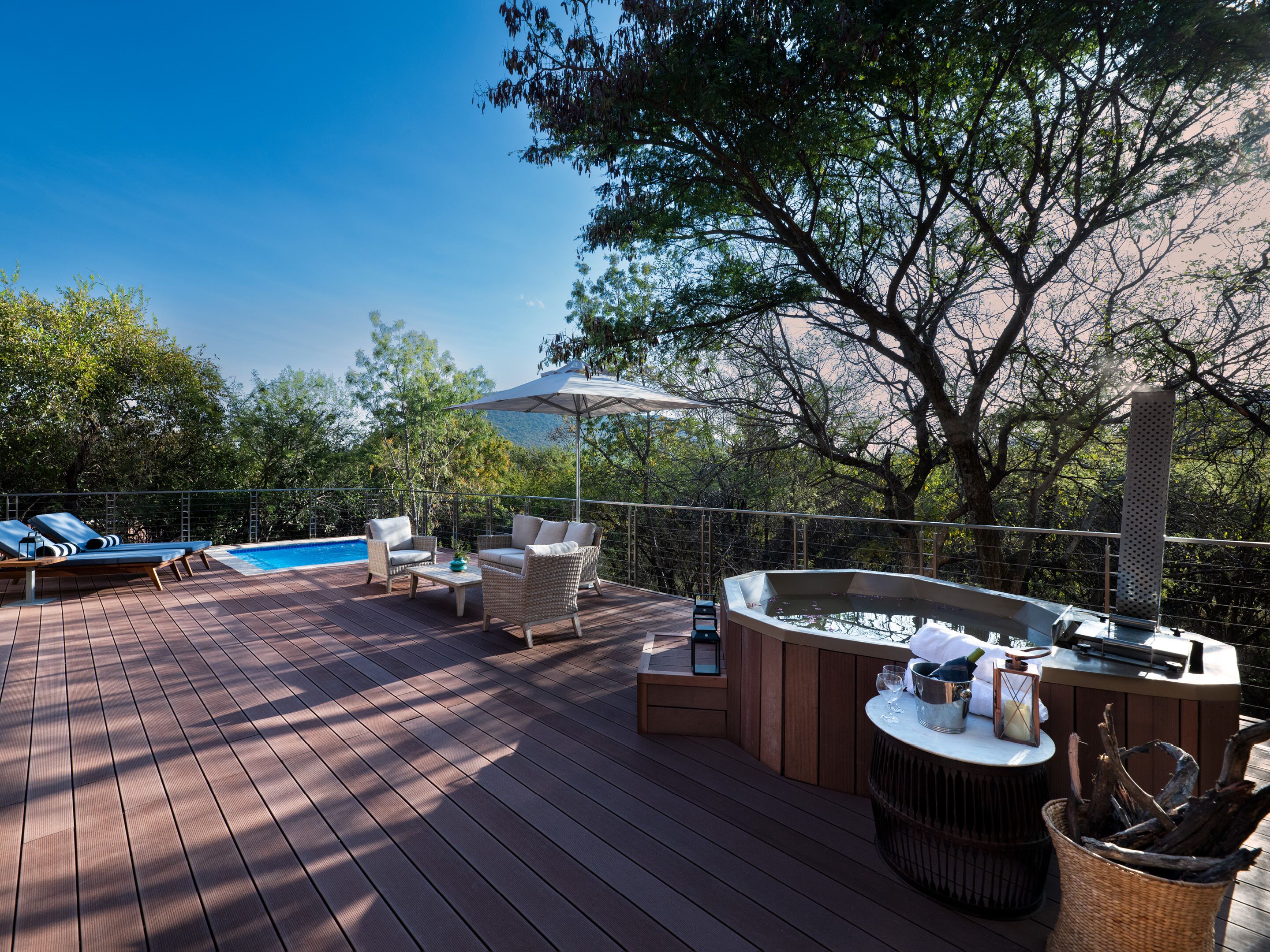 A deck with lounge chairs, a hot tub, and a pool.